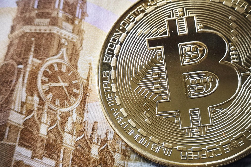 A souvenir crypto token is seen pictured with a 100 ruble bill in Moscow on July 30, 2024.