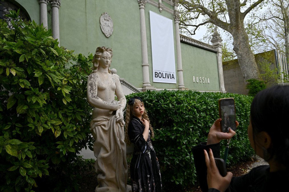 A visitor poses near a statue outside Russia's pavilion that has been attributed to Bolivia during the pre-opening of the Venice Biennale art show, on April 17, 2024 in Venice. (Source: Getty Images)