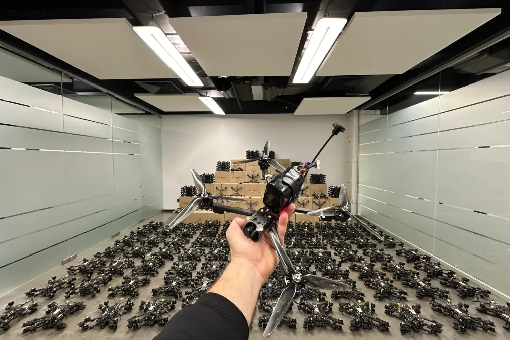 A Ukrainian-made FPV interceptor drone held in the foreground, with hundreds of identical units prepared for deployment in the background. (Source: TAF Industries)