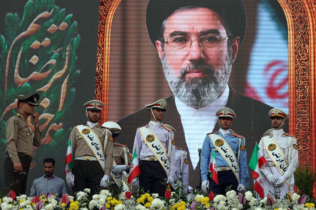 Iranian army soldiers stand in front of a picture of Iran’s supreme leader Ayatollah Mojataba Khamenei during a rally. (Source: Getty Images)