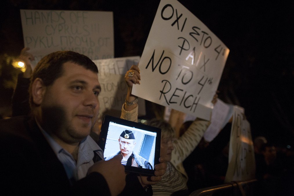 Illustrative image. A demonstrator holds an iPad with a photo of Vladimir Putin, Russia’s leader, while protesting outside the parliament in Nicosia, Cyprus, on March 21, 2013. (Source: Getty Images)
