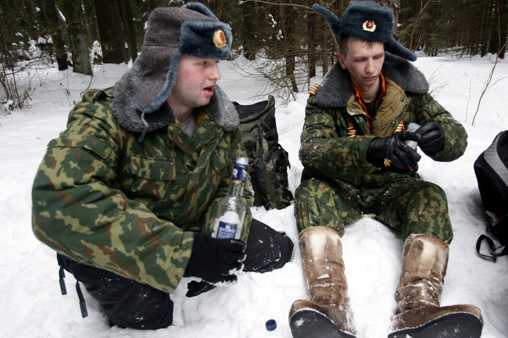 Fotografía de archivo de hombres con uniformes de oficiales del ejército ruso consumiendo bebidas alcohólicas al aire libre en un área boscosa.