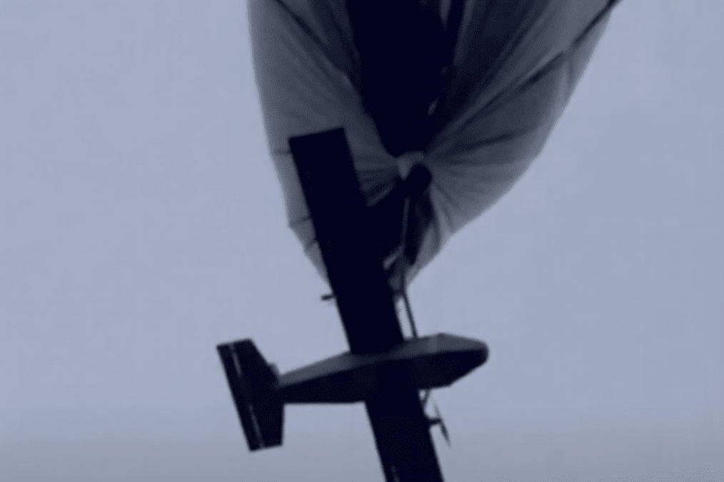 A strike drone hangs beneath a high-altitude tethered aerostat before being released. (Source: Under Fire News)