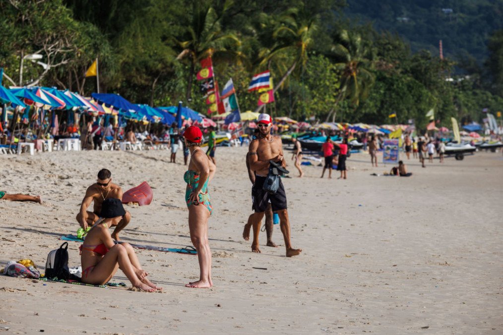 Visitors sit and walk along Patong Beach in Phuket, Thailand. (Source: Getty Images)
