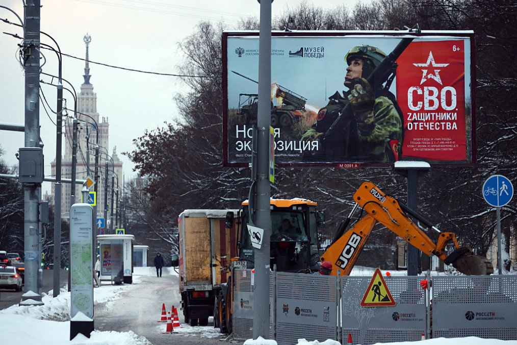 A man strolls along the sidewalk next to a billboard advertising a new exhibition at the Victory Museum dedicated to Russian participants in the war against Ukraine, on January 4, 2026, in Moscow, Russia. (Source: Getty Images)