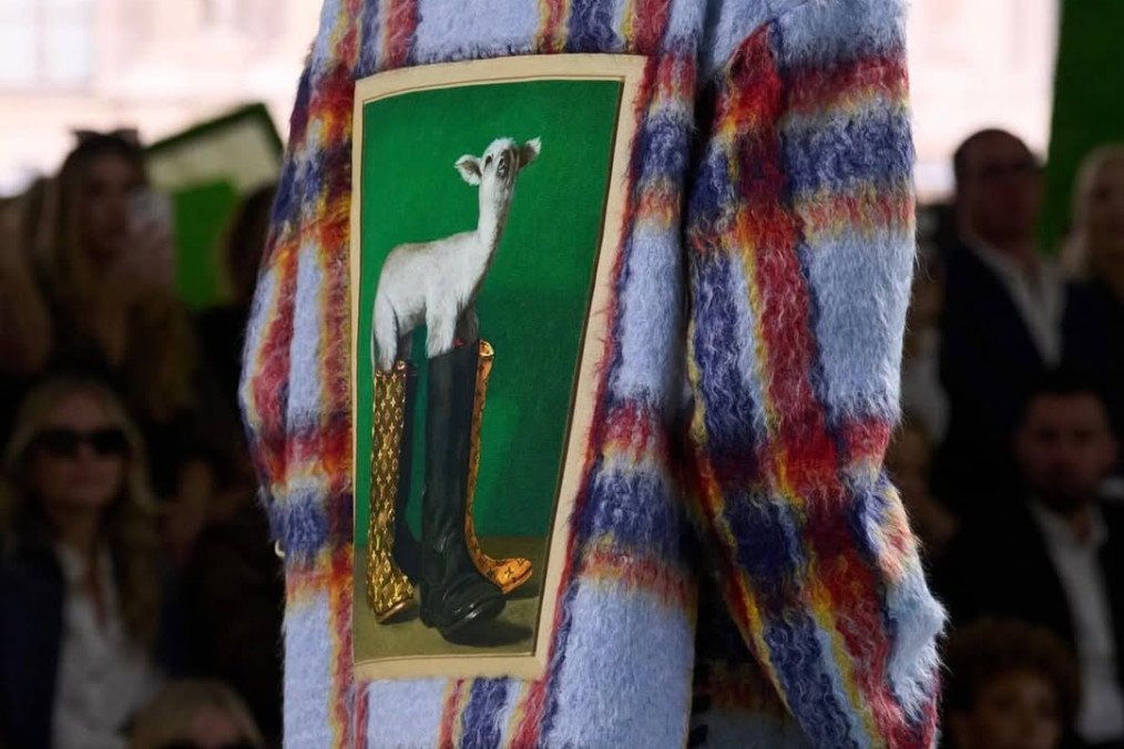 A model walks the runway showcasing a Louis Vuitton creation featuring a print of Nazar Strelyaiev-Nazarko's artwork Paramnesia (2023), where a lamb is depicted wearing luxury boots. (Source: Nazar Strelyaiev-Nazarko's/Instagram)
