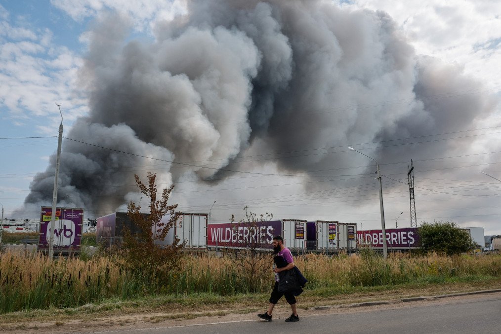 A Wildberries emloyee walks past a plume of smoke rises during a fire at Russian e-commerce firm Wildberries' logistics complex near the town of Podolsk, outside Moscow on August 16, 2026. (Source: Getty Images)