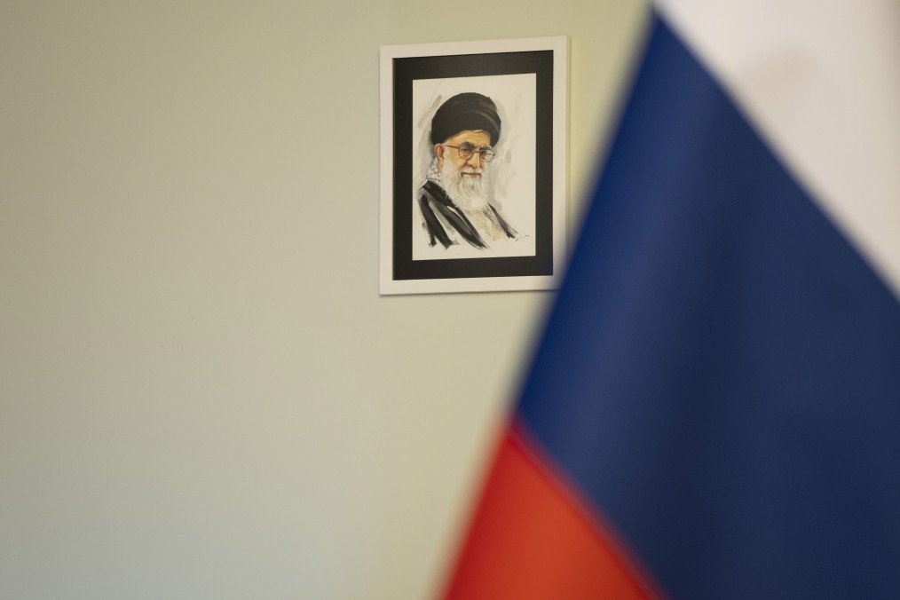 A portrait of Iran’s Supreme Leader, Ayatollah Ali Khamenei, appears next to a Russian flag before a news conference at the Vahdat Hall in downtown Tehran, Iran, on June 10, 2025. (Source: Getty Images)