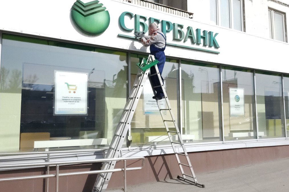 A worker installs a sign on the Sberbank's branch building April 1, 2024, in Moscow, Russia.
