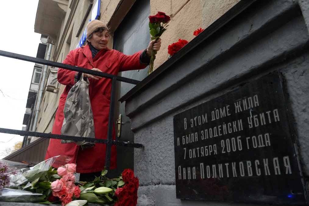A woman lays flowers next to a plaque in Moscow, which translates as “Anna Politkovskaya lived in this house and was villainously killed on October 7, 2006” on the apartment building where she was killed, October 7, 2016. (Source: Getty Images)