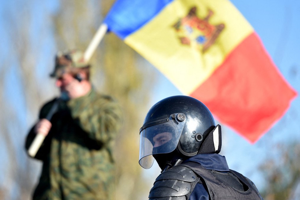 Moldova Warns Its Citizens in Russia of Risk of Being Drafted Under New Military Law A man holds Moldovan national flag as a special police officer patrols a street near a polling station during the second round of Moldova's presidential election in the town of Varnita at Moldova on November 15, 2020. (Source: Getty Images)