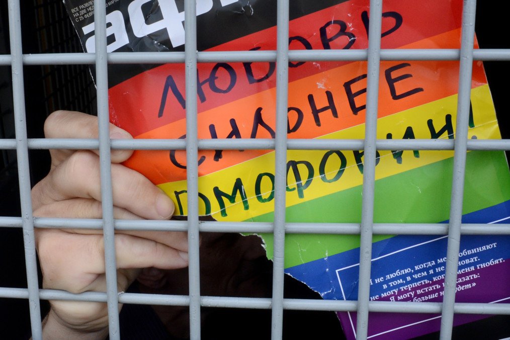 A Russian gay and LGBT rights activist shows a sign reading "Love is stronger than homophobia" from inside a Russian riot police van during an unauthorized gay rights activists rally in central Moscow on May 25, 2013.(Source: Getty Images)