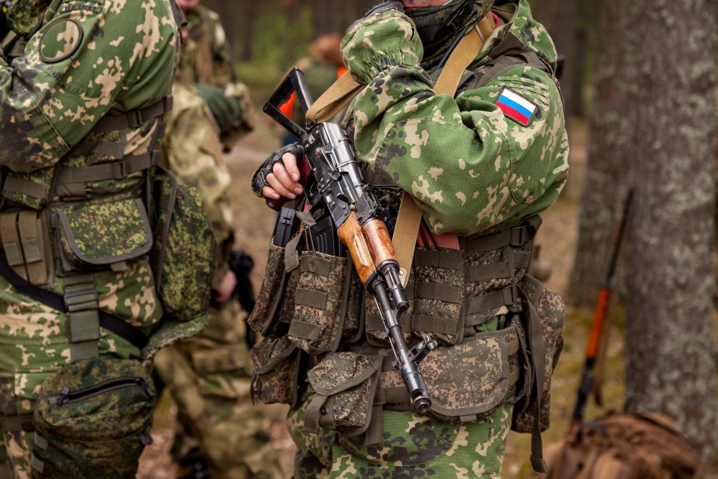 Close up hands russian soldier man dressed military camouflage uniform holds weapon in woodland at soldiers background. (Source: Getty Images)