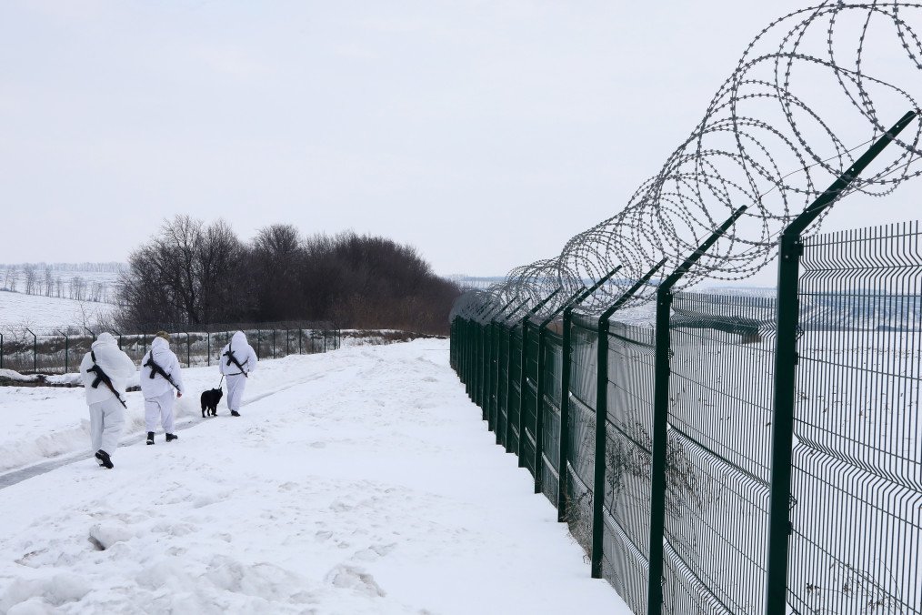 Illustrative image. Three border guards in snow camouflage uniforms and a black service dog are on a patrol mission at the Ukraine-Russia border, Kharkiv region, northeastern Ukraine, on February 16, 2022. (Source: Getty Images)