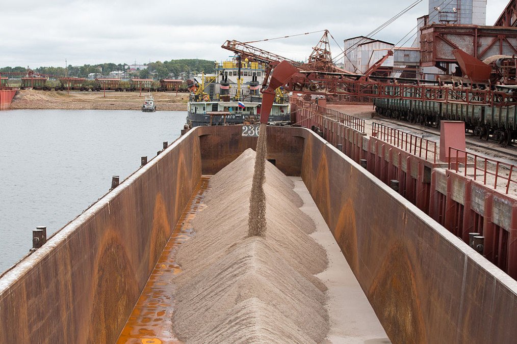 Potash grain falls into the hold of a cargo vessel during loading operations at the river port operated by OAO Uralkali in Solikamsk, Russia, on Sunday, August 25, 2013. (Source: Getty Images)
