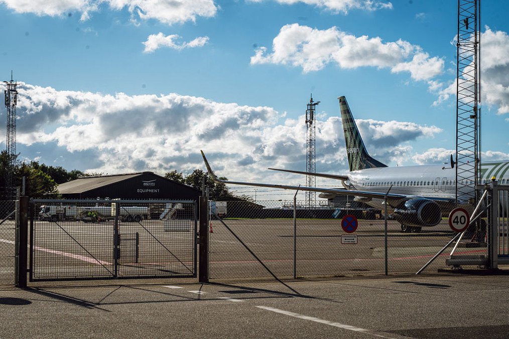 A passenger aircraft behind security fencing, suspected drone sightings at Aalborg Airport in Norresundby, Denmark, on September 26, 2025. (Source: Getty Images)