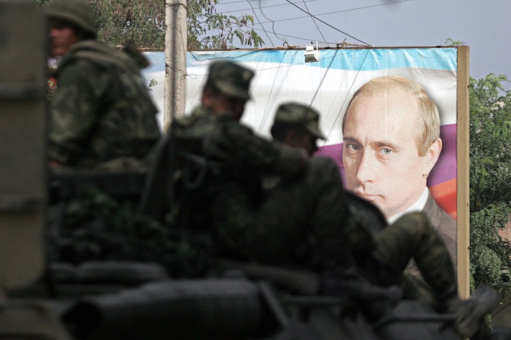 An armoured troop-carrier with Russian soldiers on the top passes a banner featuring a portrait of Russian leader Vladimir Putin as they leave eave South Ossetian capital Tskhinvali on August 25. (Source: Getty Images) An armoured troop-carrier with Russian soldiers on the top passes a banner featuring a portrait of Russian leader Vladimir Putin as they leave eave South Ossetian capital Tskhinvali on August 25. (Source: Getty Images)