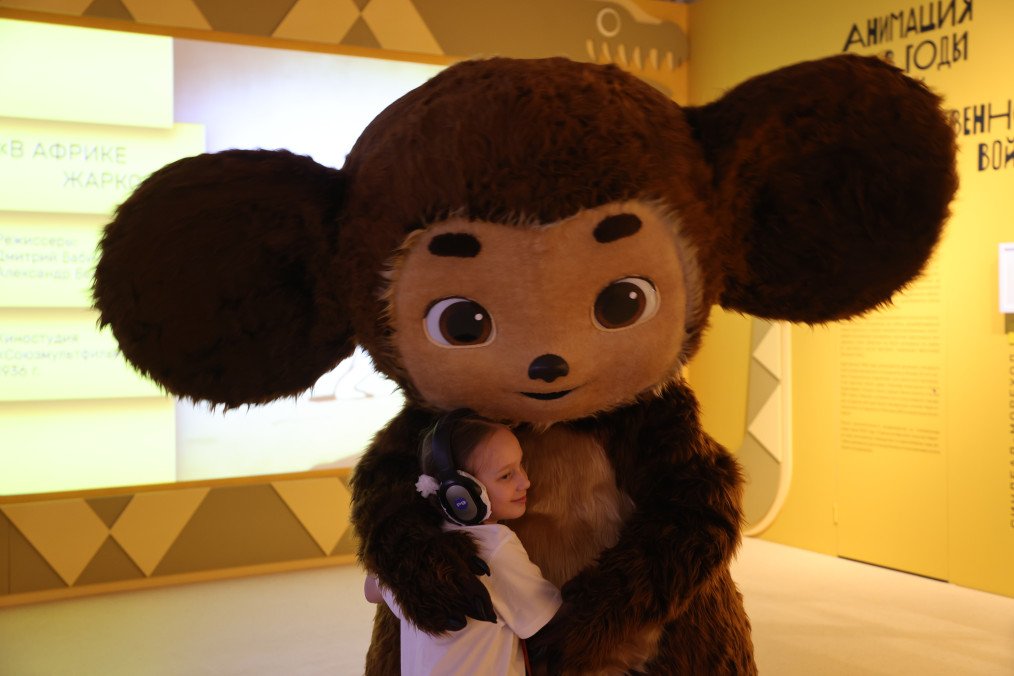 A young girl embraces a performer dressed as Cheburashka, a Soviet-era cartoon character at the "Live Together" exhibition May 15, 2023 in Moscow, Russia. (Photo: Getty Images)
