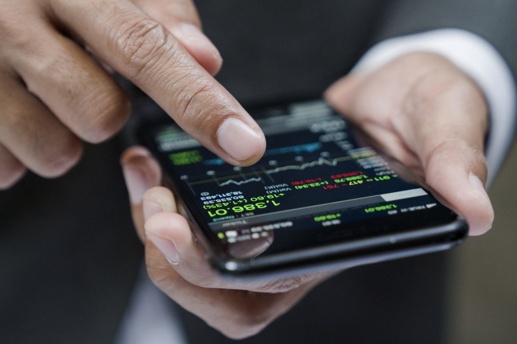 Businessman using a mobile phone to check stock market data. Illustrative photo. (Source: Getty Images)