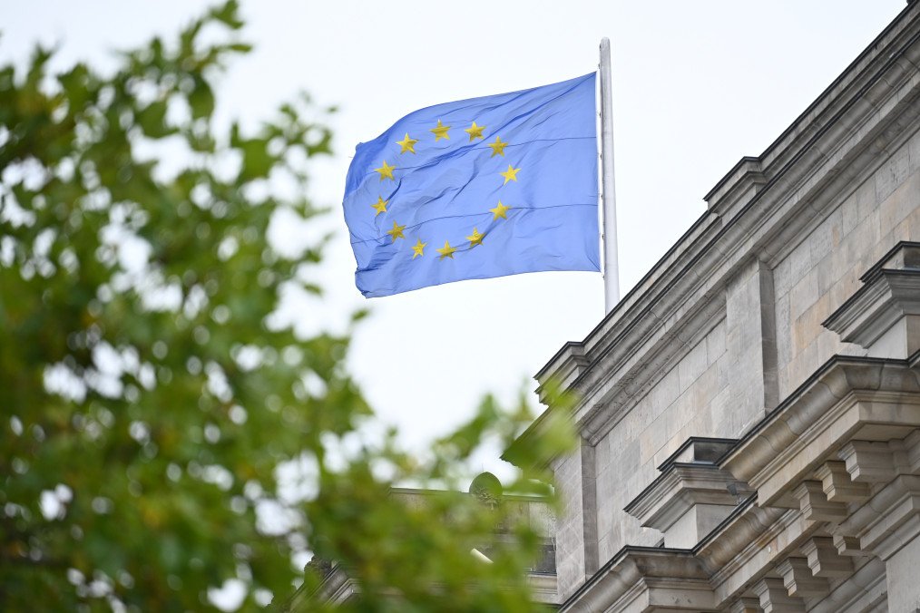 A European flag can be seen behind the leaves of a tree on the Reichstag building on October 10, 2025. (Source: Getty Images)