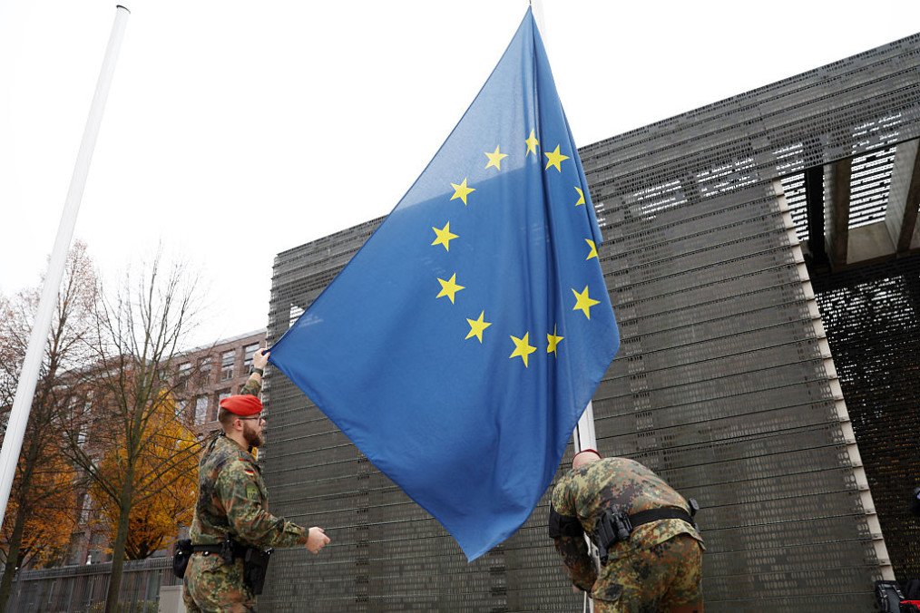 Kaja Kallas y ministros de defensa de la UE discutiendo el manual de defensa mutua frente a un mapa de Europa en Bruselas.