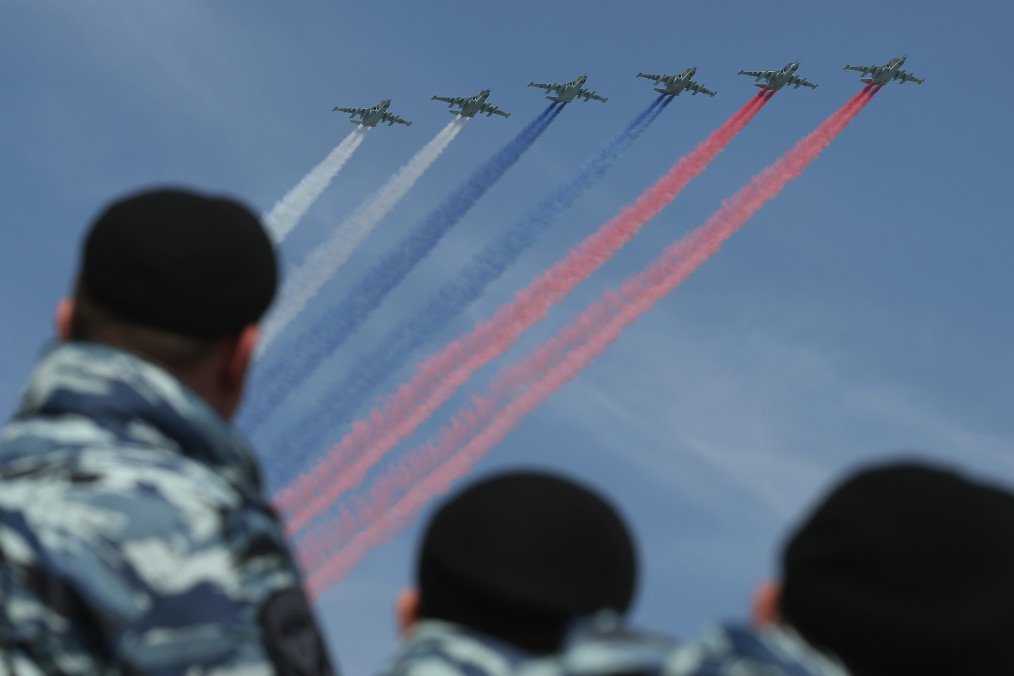 Security personnel watch as Russian air force fighter jets trail the colors of the Russian flag.  (Source: Getty Images)