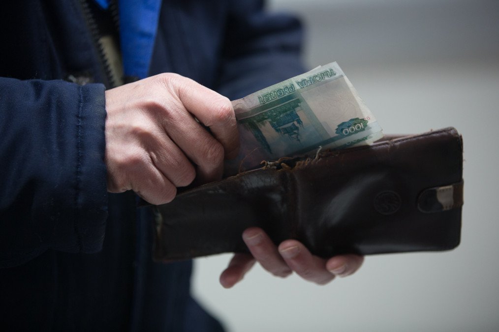 Survey Shows 60% of Russians See Worsening Economy as Income Growth Halts A customer handles 1000 ruble banknotes from a wallet. (Source: Getty Images)