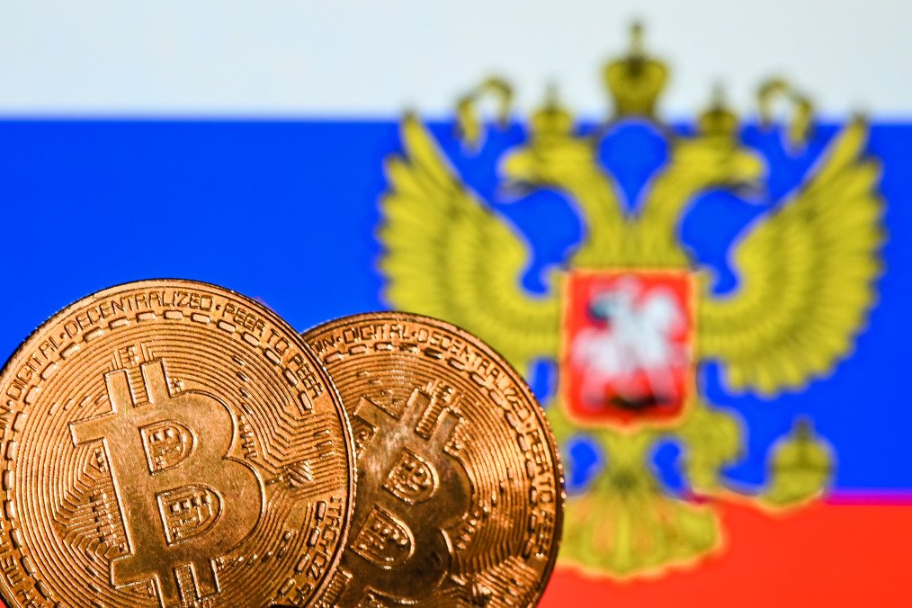 Illustrative image of two commemorative bitcoins seen in front of the national flag of Russia displayed on a computer screen. (Source: Getty Images)