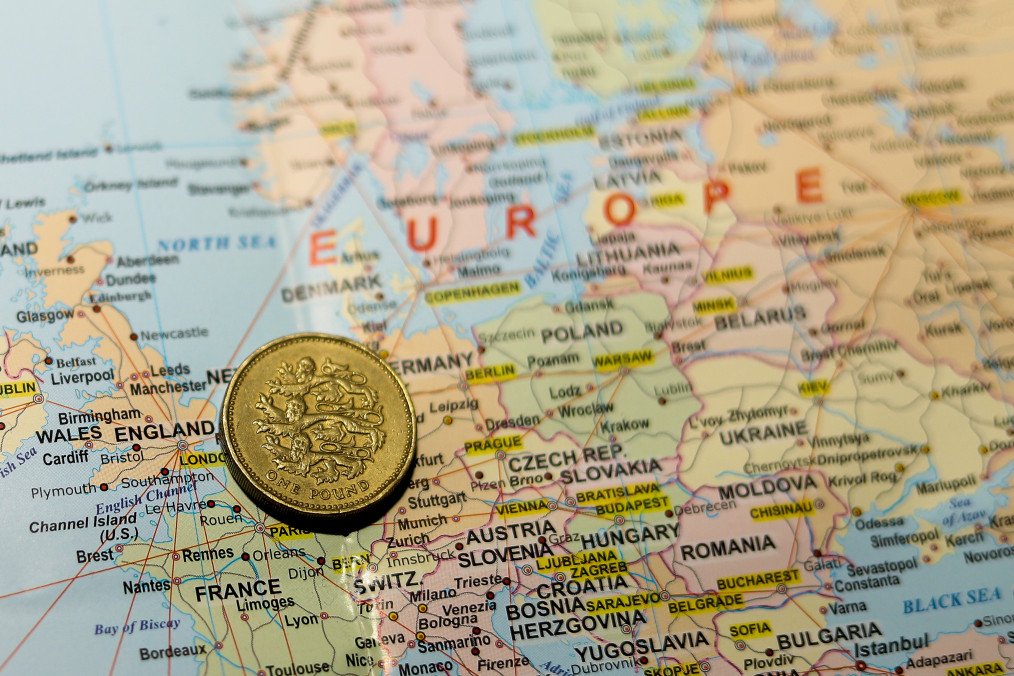 A one-pound coin from the United Kingdom placed over the map of Europe.