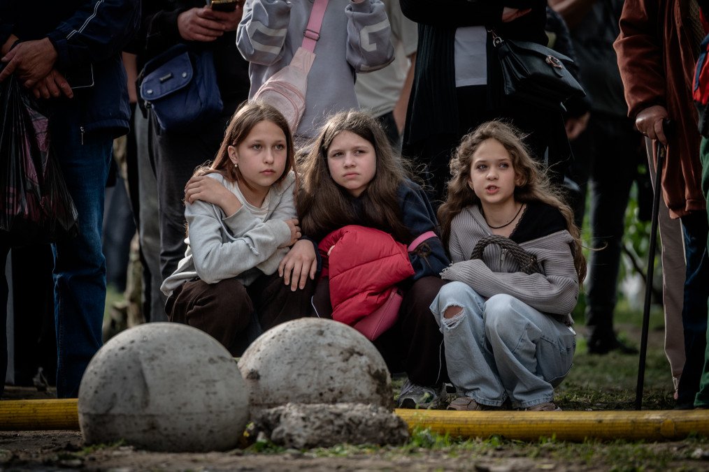 Russia Sends Ukrainian Children to Military Camps Under Guise of Free Vacation People sit on a street near a destroyed building while waiting for news about the missing on May 14, 2026 in Kyiv, Ukraine. Illustrative photo. (Source: Getty Images)
