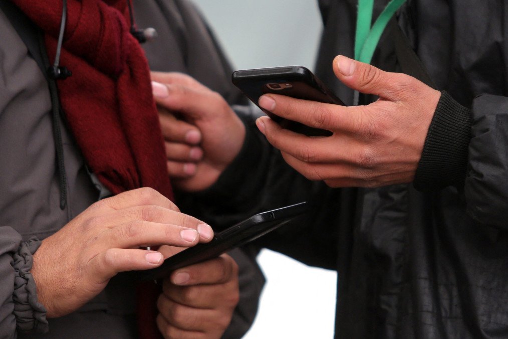Russia Uses Fake ATESH Accounts and Messaging Bots to Expose Resistance Helpers People hold smartphones in their hands. Illustrative image. (Source: Getty Images)