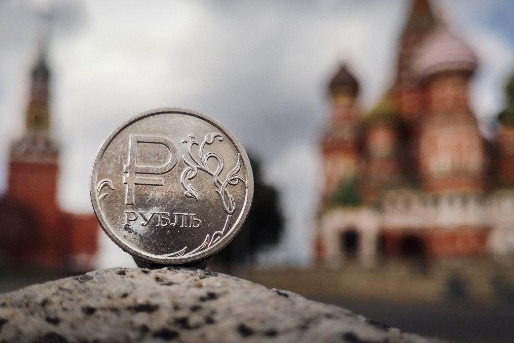 A Russian ruble coin is pictured in front of the Kremlin’s Spasskaya tower and St. Basil’s Cathedral in downtown Moscow on September 12, 2025. (Source: Getty Images)