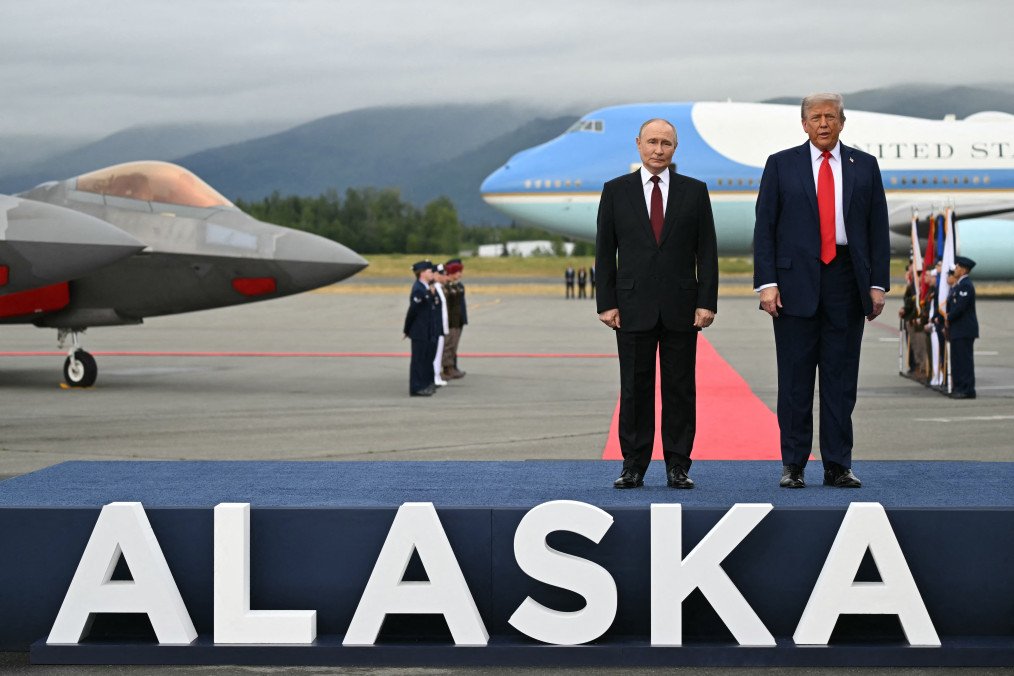 Russian leader Vladimir Putin and US President Donald Trump pose on a podium on the tarmac after arrival at Joint Base Elmendorf-Richardson in Anchorage, Alaska, on August 15, 2025. (Source: Getty Images)