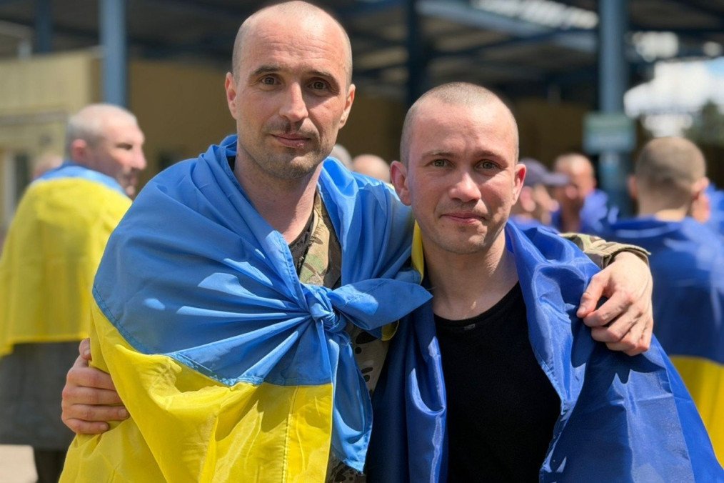 Un grupo de soldados ucranianos sonríen y se abrazan con banderas azules y amarillas sobre los hombros tras ser liberados del cautiverio ruso el 5 de junio de 2026.