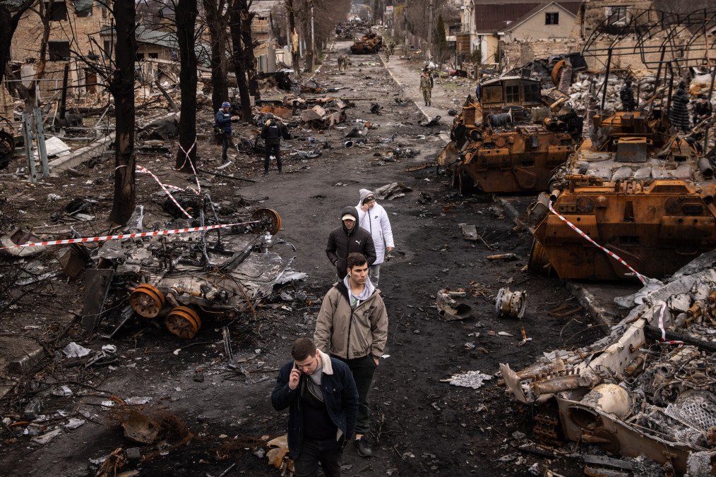 People walk through debris and destroyed Russian military vehicles on a street on April 06, 2022 in Bucha, Ukraine. (Source: Getty Images)