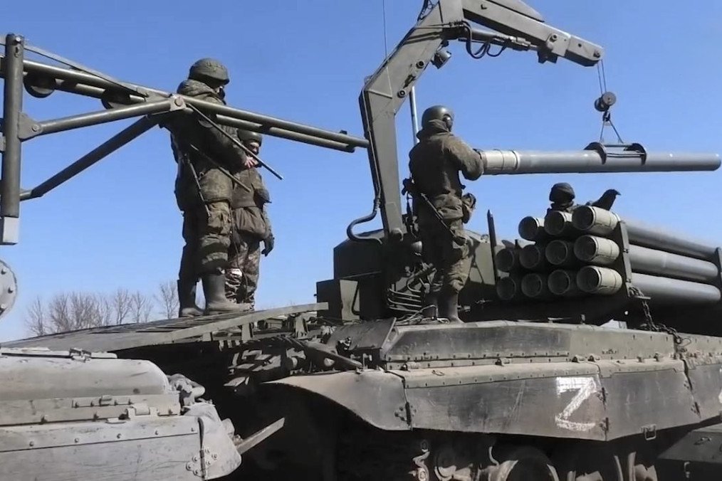 Russian soldiers load thermobaric rockets onto a TOS-1 heavy flamethrower system using a crane arm. (Source: Russian media)