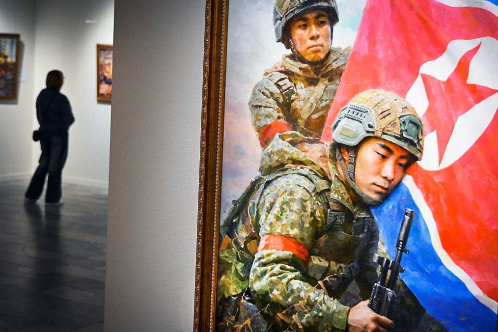 A visitor walks next to the painting “The Sons of the Motherland” by Kim Yeong Chan during North Korean arts exhibition in Moscow on October 2, 2025. (Source: Getty Images)
