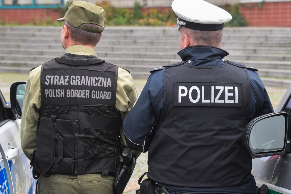A federal police officer and a Polish border guard stand between their new vehicles. Illustrative photo. (Source: Getty Images)