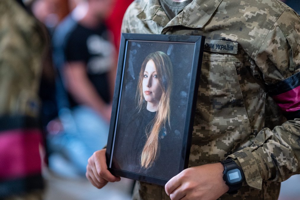 A soldier of the honor guard holds a portrait of Victoria Amelina during a funeral service in front of the Saint Peter and Paul Garrison Church on July 5, 2023 in Lviv, Ukraine. (Source: Getty Images)