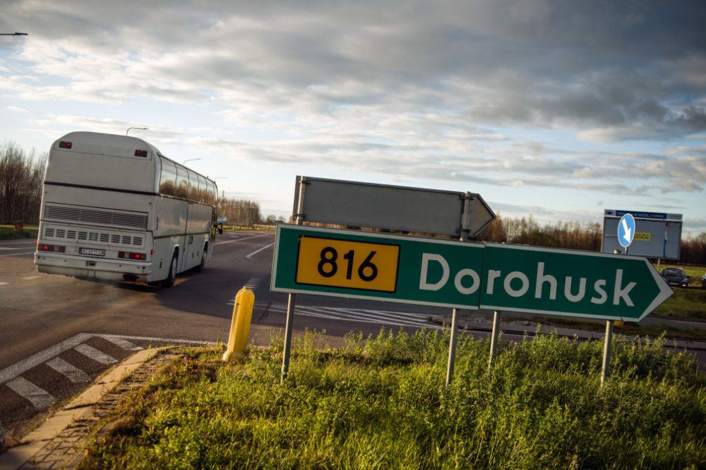 A Ukrainian bus is passing by a road sign with directions to the border town of Dorohusk, Poland. (Source: Getty Images)