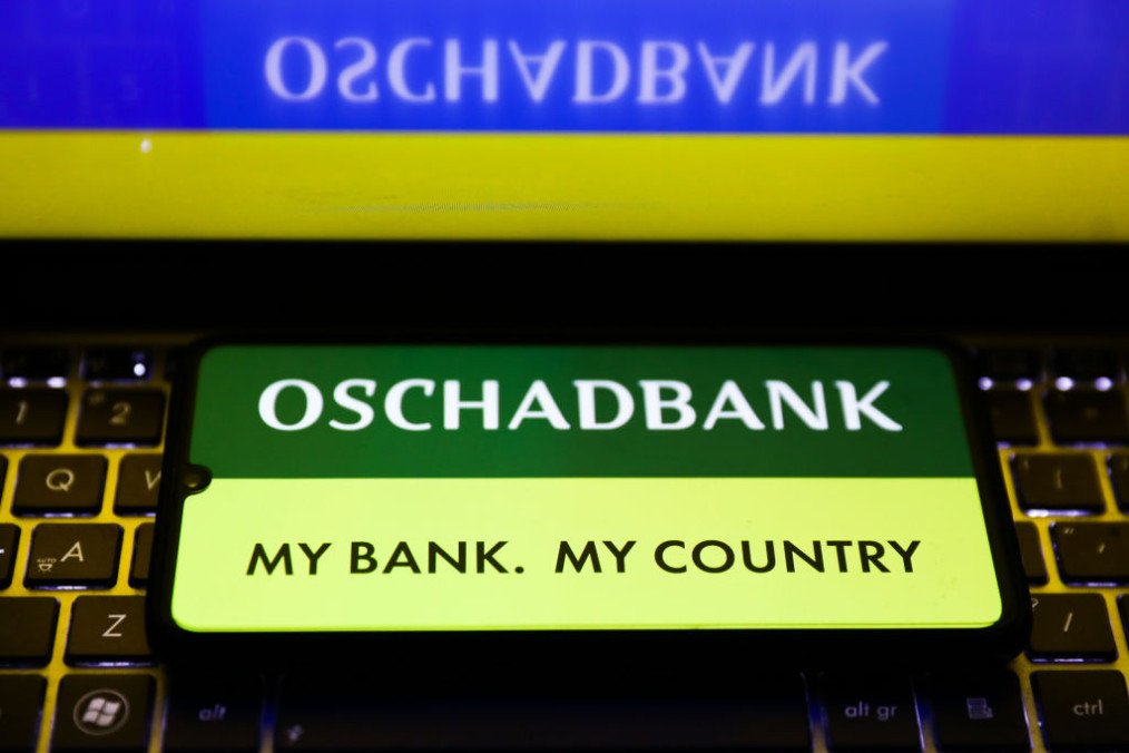 Oschadbank logo is displayed on a mobile phone screen photographed for the illustration photo taken in Krakow, Poland on February 15, 2022. (Source: Getty Images)