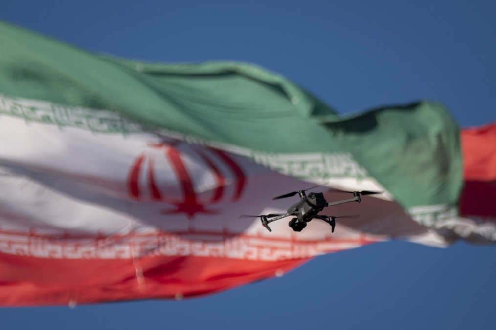 A drone flies in front of an Iranian flag. (Source: Getty Images)