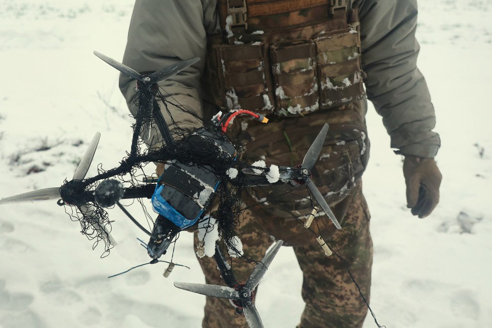 A soldier of Ukraine’s 13th Khartiia Brigade displays an FPV drone caught in a net during field tests of a net-launching counter-drone system, January 7, 2026. (Source: Getty Images)