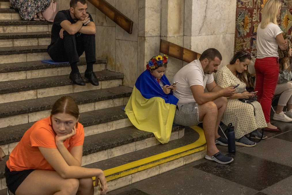 A young girl wearing a Ukrainian national flag sits on a stairway as people take shelter in the Khreshchatyk metro station during an air-raid alert on Ukraine's Independence Day in Kyiv, on August 24, 2023. A young girl wearing a Ukrainian national flag sits on a stairway as people take shelter in the Khreshchatyk metro station during an air-raid alert on Ukraine's Independence Day in Kyiv, on August 24, 2023.