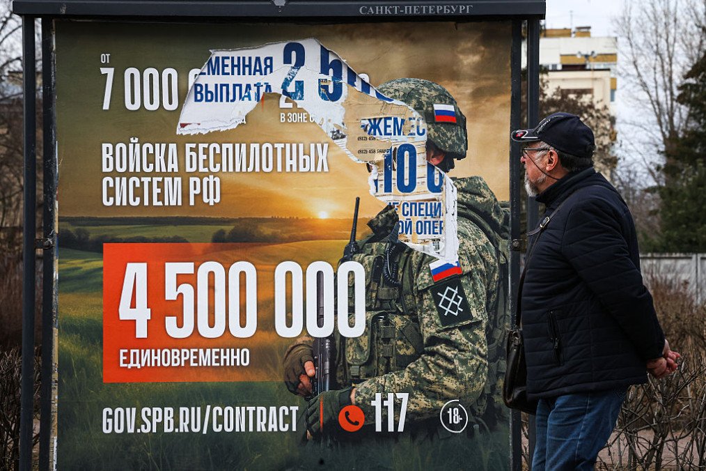 A man walks past an information billboard advertising contract service in the Russian Armed Forces, installed on one of the city streets. (Source: Getty Images)