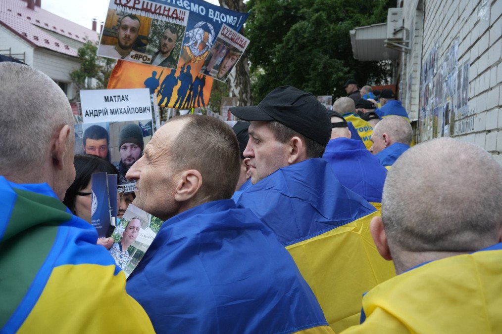 Ukraine Prepares Next Phase of Prisoner Swap as HUR Details “1000-for-1000” Format Former prisoners of war, draped in Ukrainian flags, gather outside the exchange site on June 19, 2025. (Source: Joshua Olley/UNITED24 Media)