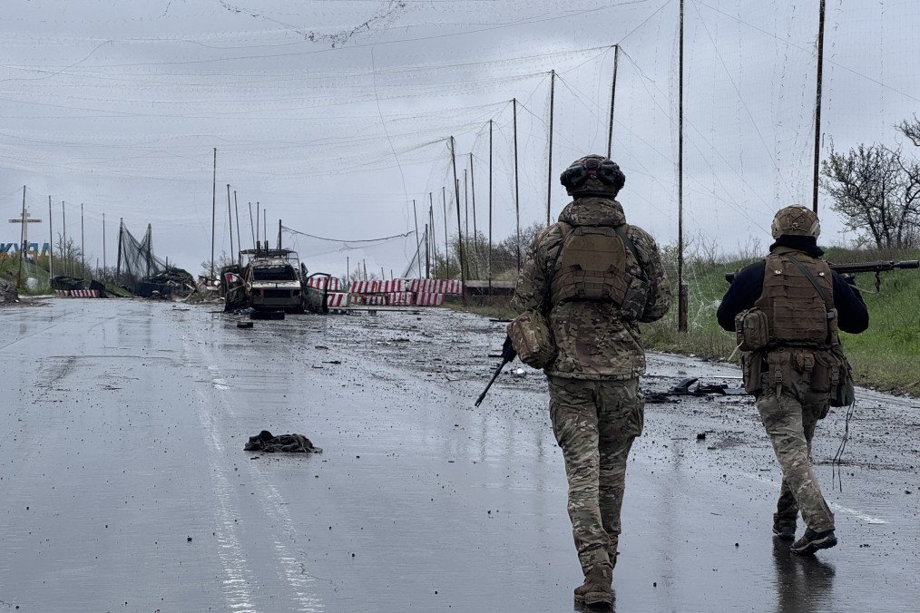 Ukrainian infantrymen walk in front of a burned car wreckage at an abandoned checkpoint next to Druzhkivka stele on Kostiantynivka-Kramatorsk road on April 24, 2026 in Donetsk region, Ukraine. (Source: Getty Images)