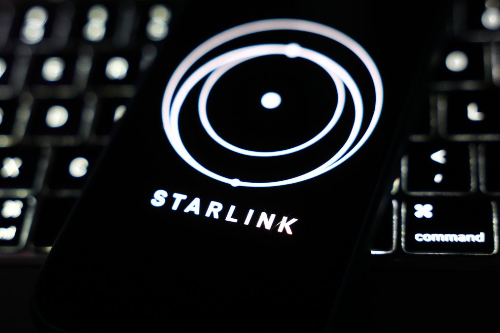 A laptop keyboard and Starlink logo displayed on a phone screen are seen in this illustration photo taken in Krakow, Poland on March 11, 2025. (Source: Getty Images)