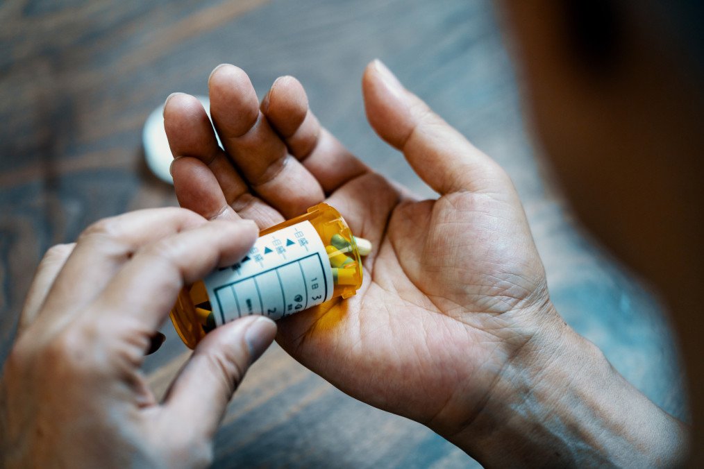 Close-up of a male hand holding a pill bottle pouring medication into his hand in his house. (Source: Getty Images)