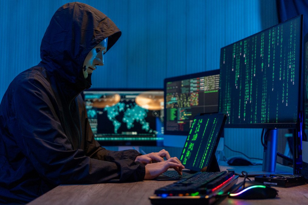 Polish Police Arrest Russian Suspect Accused of Hacking Corporate IT Networks Anonymous computer hacker in white mask and hoodie. Obscured dark face using laptop computer for cyber attack and calling on cellphone. Illustrative photo. (Source: Getty Images)